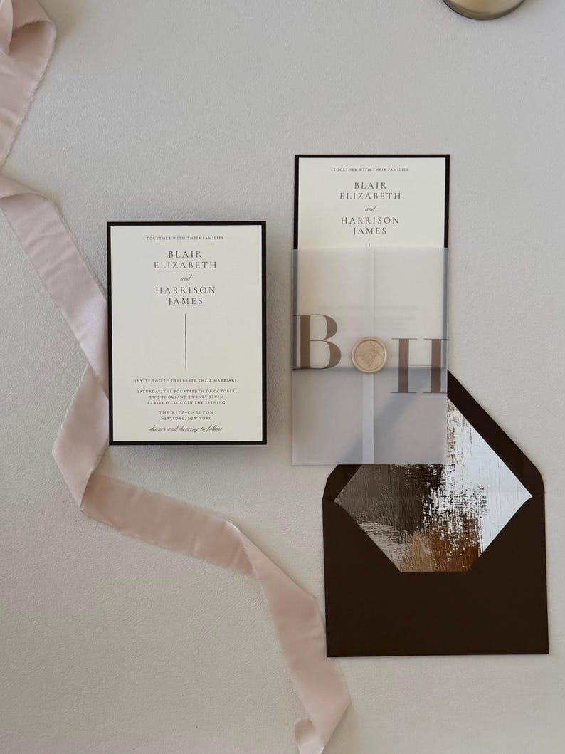 Elegant Blair wedding invitation displayed with translucent monogram vellum, soft blush ribbon and a brown envelope opened to reveal a romantic floral liner.