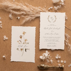May include: Wedding invitation with a floral design. The invitation is for Mollie Jade Firebaugh and Ethan Kane Castro. The wedding will take place on Saturday, July 11, 2023 at 5:00 PM at Pinewoods Inn in Cambridge, Minnesota.