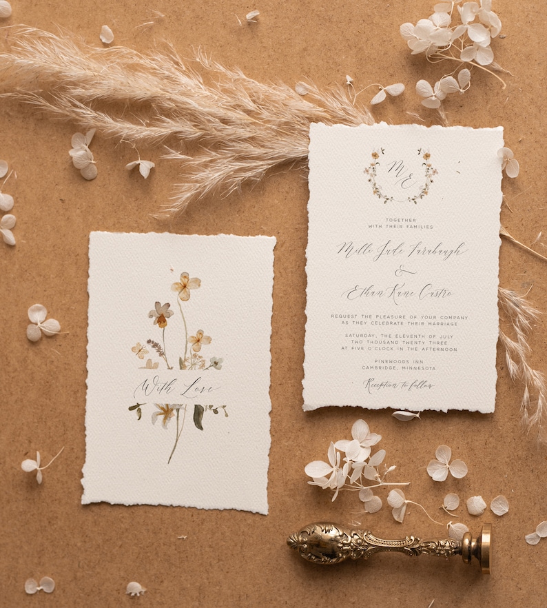 May include: Wedding invitation with a floral design. The invitation is for Mollie Jade Firebaugh and Ethan Kane Castro. The wedding will take place on Saturday, July 11, 2023 at 5:00 PM at Pinewoods Inn in Cambridge, Minnesota.