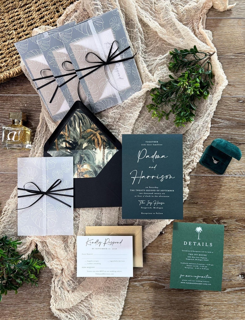 Aged, antique style palm tree wedding invitation, green, gold and black, white ink on dark green printed invitation, monstera leaf vellum jacket, black ribbon