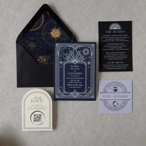 Black A7 wedding envelope opened to reveal a navy and antique gold astronomical star chart liner, paired with the Elara navy blue wedding invitation, black details card, ivory arch RSVP, and coordinating celestial tag.