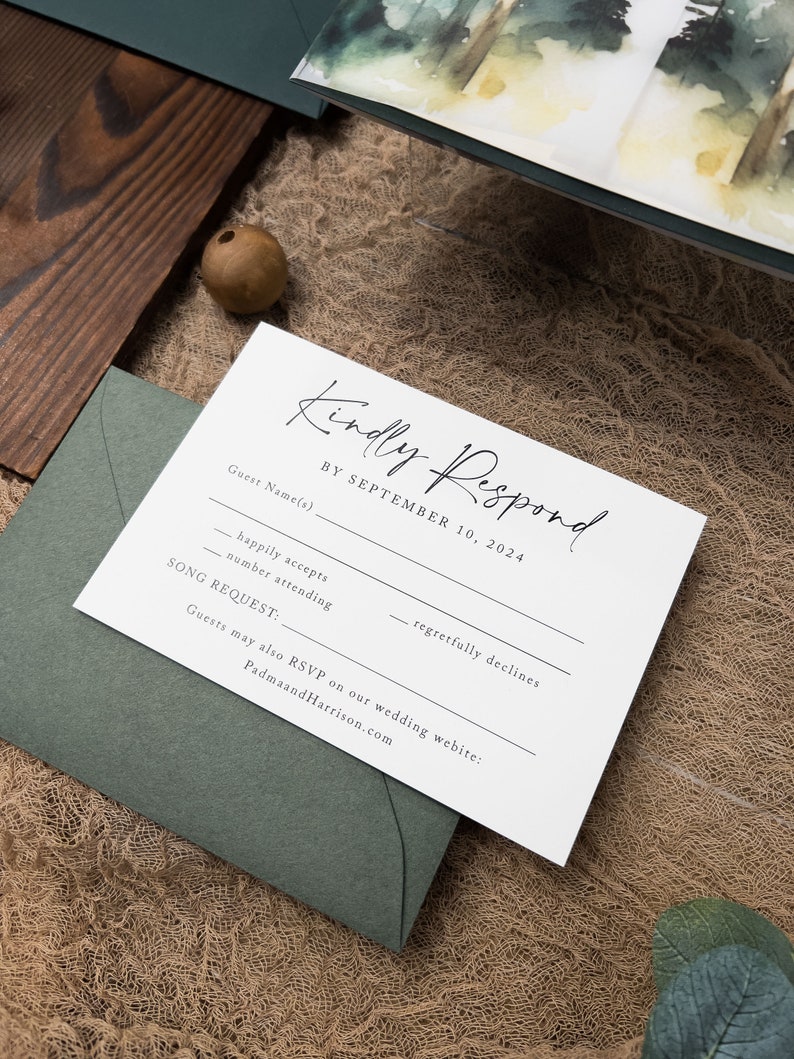 May include: A white RSVP card with black text. The card has a section for the guest's name, a checkbox for happily accepts, a checkbox for regretfully declines, a space for the number attending, and a space for a song request. The card also includes the text "Kindly Respond by September 10, 2024" and "Guests may also RSVP on our wedding website: PadmaandHarrison.com".