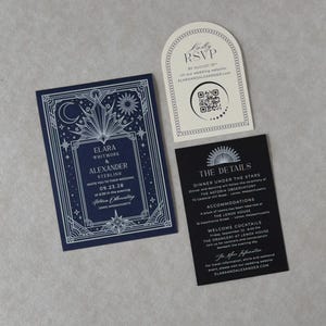 Navy blue celestial wedding invitation with ornate silver Art Deco border displayed beside a black wedding details card, ivory arch RSVP card, and lavender moon and stars tag on a soft neutral background.