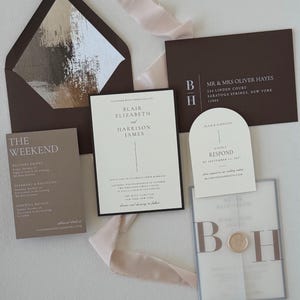 Neutral ivory and brown Blair wedding invitation suite featuring a bordered invitation, translucent monogram vellum wrap, arch RSVP card, brown details card and coordinating envelope with floral liner.