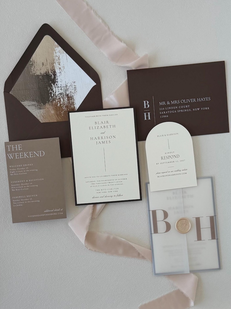 Neutral ivory and brown Blair wedding invitation suite featuring a bordered invitation, translucent monogram vellum wrap, arch RSVP card, brown details card and coordinating envelope with floral liner.