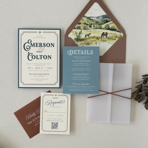 Complete western wedding invitation suite featuring dusty blue details card, vintage ivory invitation, brown envelope and elegant ranch-inspired stationery details.