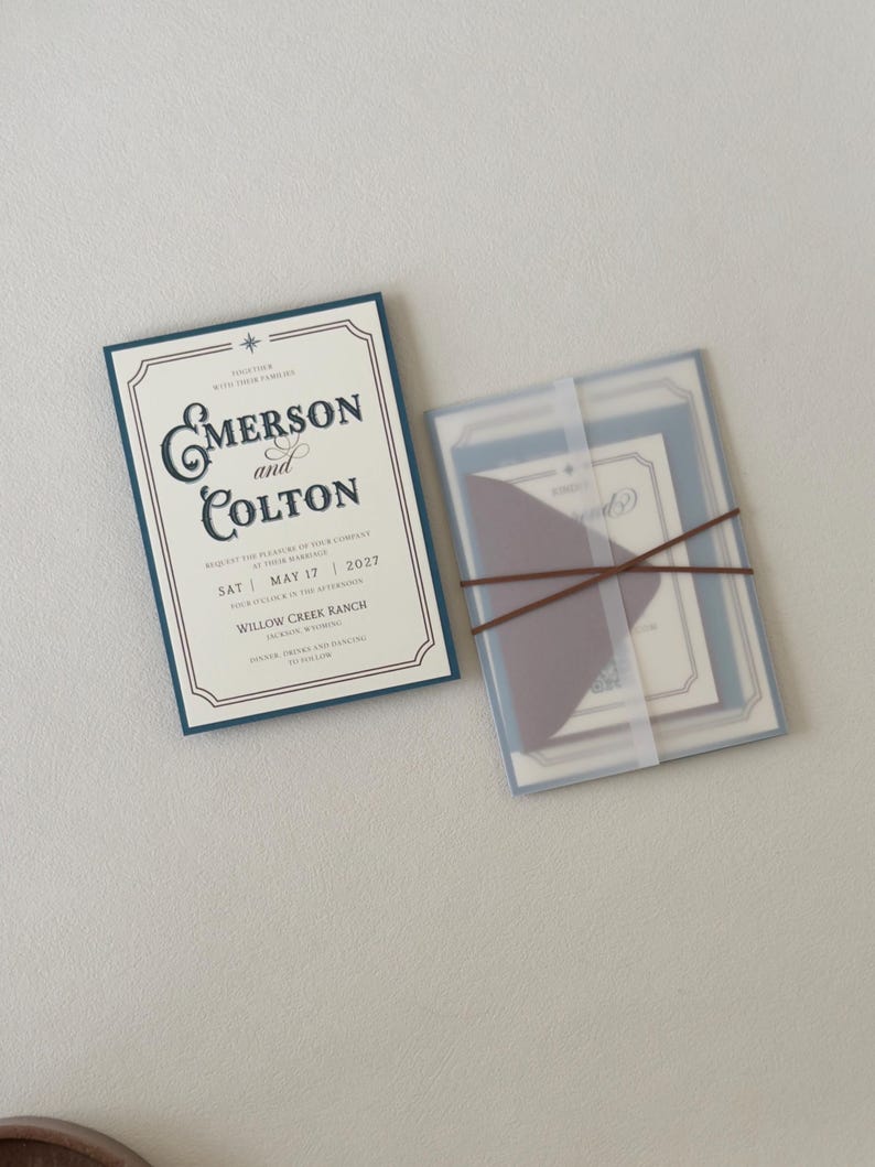 Western wedding invitation paired with translucent layered stationery tied with thin brown ribbon, featuring dusty blue and warm neutral details for an elegant ranch wedding.