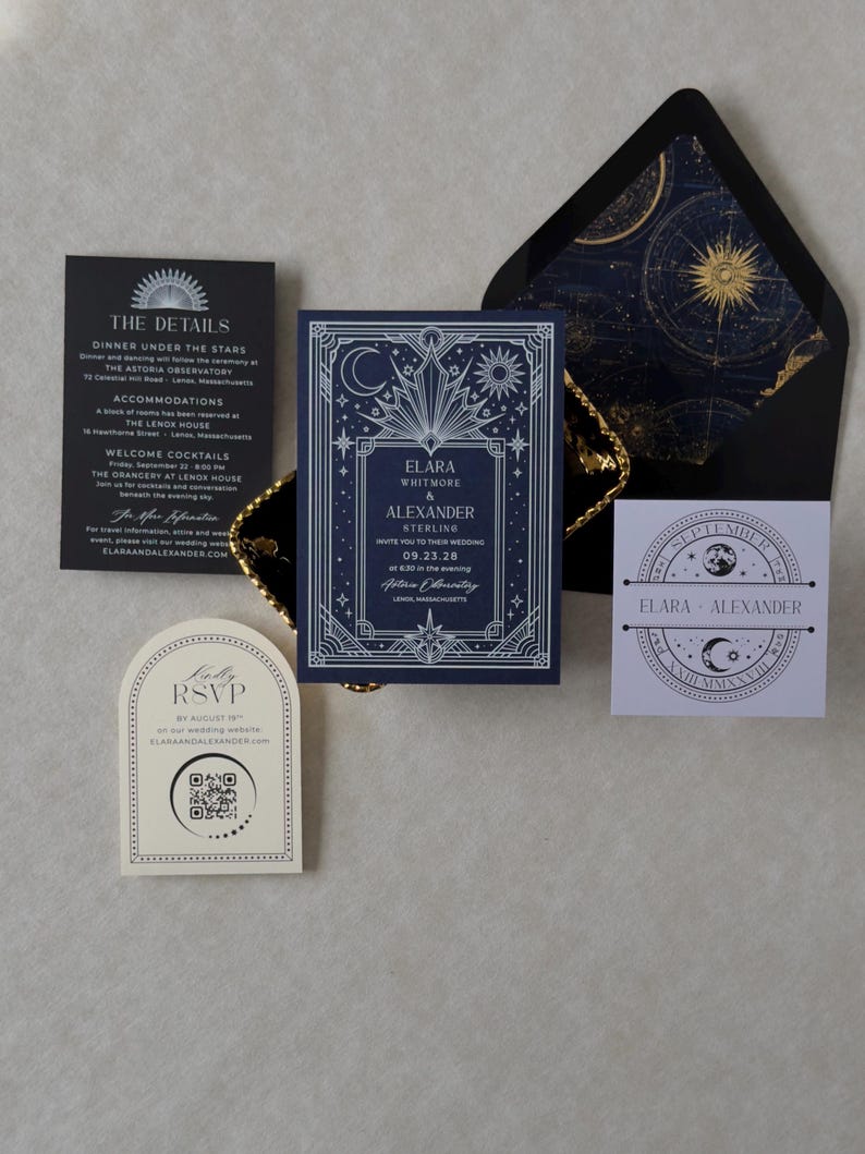 Elara navy blue wedding invitation with ornate silver Art Deco celestial border, displayed alongside a black envelope with gold astronomical liner, black details card, ivory arch RSVP, and lavender celestial tag.