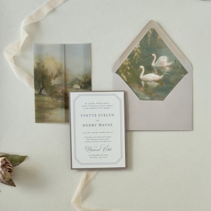 Yvette wedding invitation displayed over a scenic countryside vellum wrap with coordinating green RSVP card and dusty blue details for a romantic outdoor wedding.
