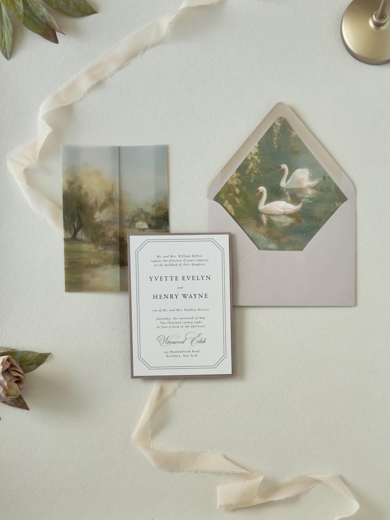 Yvette wedding invitation displayed over a scenic countryside vellum wrap with coordinating green RSVP card and dusty blue details for a romantic outdoor wedding.