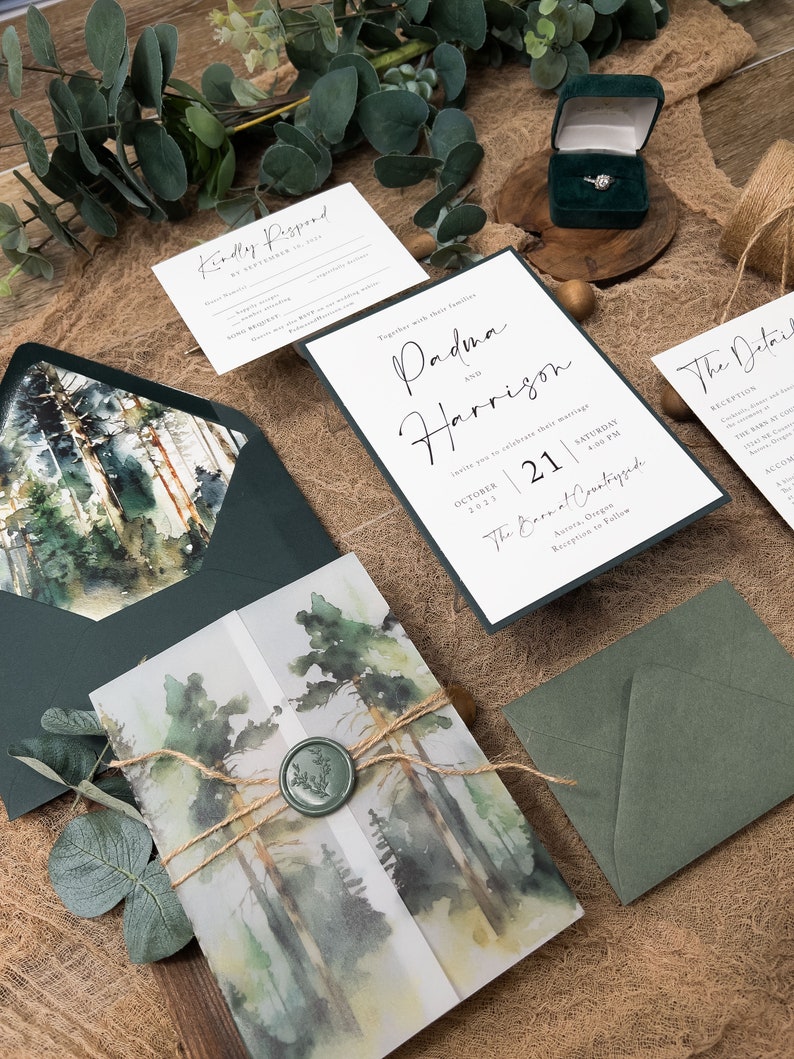 May include: Wedding invitation suite featuring a watercolour forest design. The invitation includes the text "Padma and Harrison" and the date "October 21, 2023". The RSVP card has the text "Kindly Respond by September 1st, 2023".
