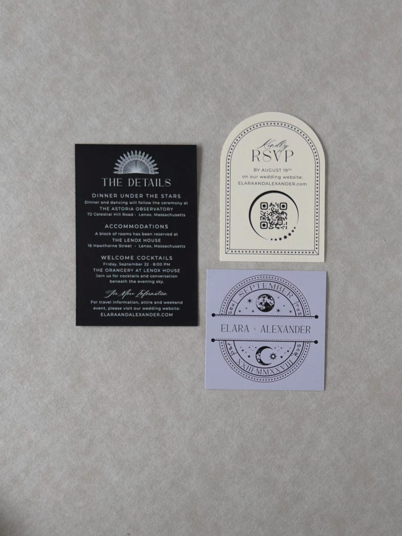 Elara wedding invitation accessories arranged on a neutral textured background, including a black details card with white printing, ivory arch-shaped RSVP card with QR code, and lavender square tag featuring a celestial moon and stars design.