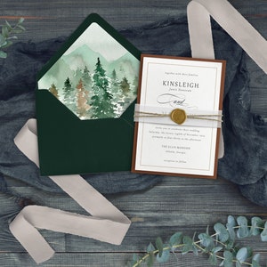 K&ouml;nnte beinhalten: Eine Hochzeitseinladung mit einem Aquarell-Waldszenario auf dem Umschlag und einer braunen Karte mit goldenen Lettern. Die Karte lautet "Kinsleigh und ... zusammen mit ihren Familien laden Sie ein, ihre Hochzeit am Samstag, den 28. November 2023, um 16:00 Uhr im THE ELLIS MANSION Atlanta, Georgia, zu feiern. Empfang im Anschluss"
