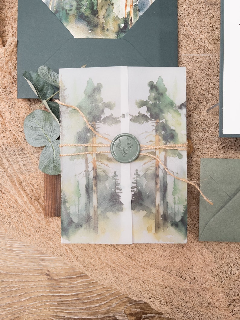 May include: A watercolour illustration of a woodland scene printed on a white paper card with a green wax seal. The card is tied with twine and is sitting on a brown hessian surface.