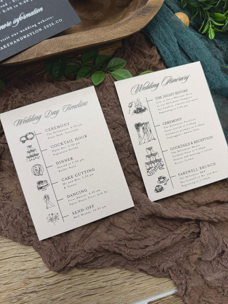 May include: Two wedding itinerary cards with elegant calligraphy. The cards detail the wedding day timeline and the night before events. The cards are on a textured brown fabric with green foliage.