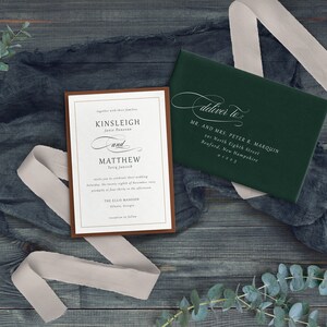 K&ouml;nnte beinhalten: Eine Hochzeitseinladung mit braunem Rand und wei&szlig;em Text. Die Einladung lautet "Gemeinsam mit ihren Familien, Kinsleigh und Matthew, Samstag, der achtundzwanzigste November, p&uuml;nktlich um 16:30 Uhr, The Ellis Mansion, Atlanta, Georgia, Empfang im Anschluss". Ein gr&uuml;ner Umschlag mit wei&szlig;em Text lautet "Zustellen an: Mr. and Mrs. Peter R. Marquin, 201 North Eighth Street, Bedford, New Hampshire 01223".