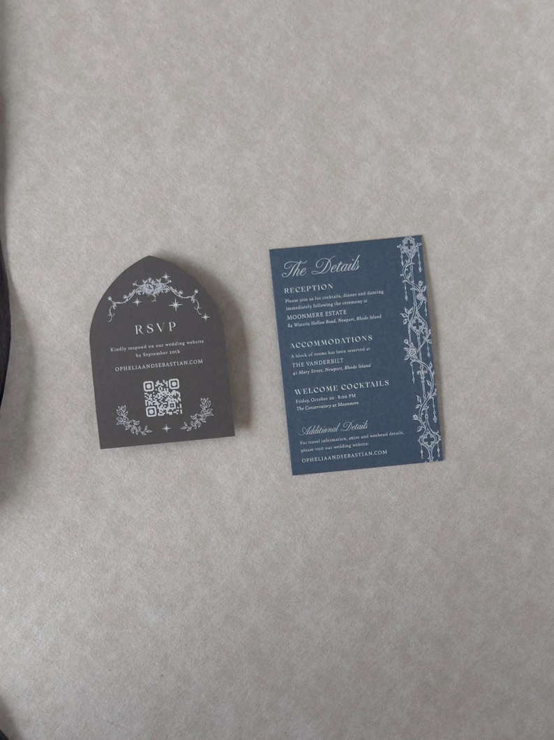 Marina blue wedding details card with white ink typography beside a Dark Grey tombstone-shaped RSVP card featuring decorative celestial artwork and a QR code for online wedding responses.