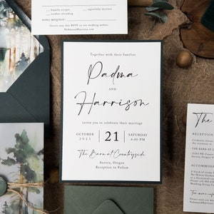 May include: A wedding invitation suite with a watercolour forest background. The invitation features the names "Padma and Harrison" in elegant calligraphy. The date is 21 October 2023, and the location is "The Barn at Countryside" in Aurora, Oregon. The reception is to follow.