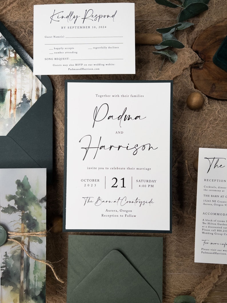 May include: A wedding invitation suite with a watercolour forest background. The invitation features the names "Padma and Harrison" in elegant calligraphy. The date is 21 October 2023, and the location is "The Barn at Countryside" in Aurora, Oregon. The reception is to follow.