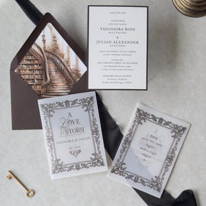 Elegant ivory literary wedding invitation with classic typography arranged alongside intricate illustrated stationery pieces and a grand staircase envelope liner, styled on a light neutral backdrop with dark ribbon.