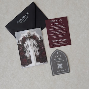 Lenore wedding invitation accessories featuring an Ebony mailing envelope with white address printing, Claret details card, Dark Grey tombstone-shaped RSVP with QR code, and coordinating dark floral stationery.