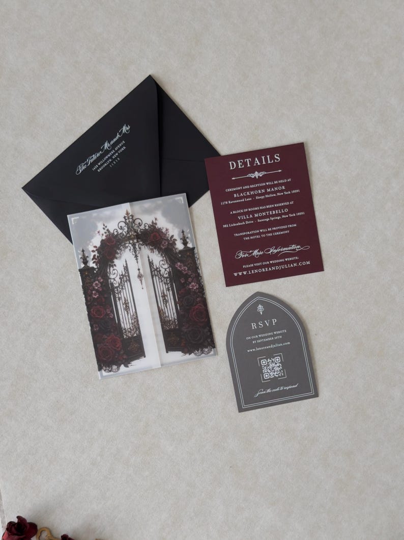 Lenore wedding invitation accessories featuring an Ebony mailing envelope with white address printing, Claret details card, Dark Grey tombstone-shaped RSVP with QR code, and coordinating dark floral stationery.