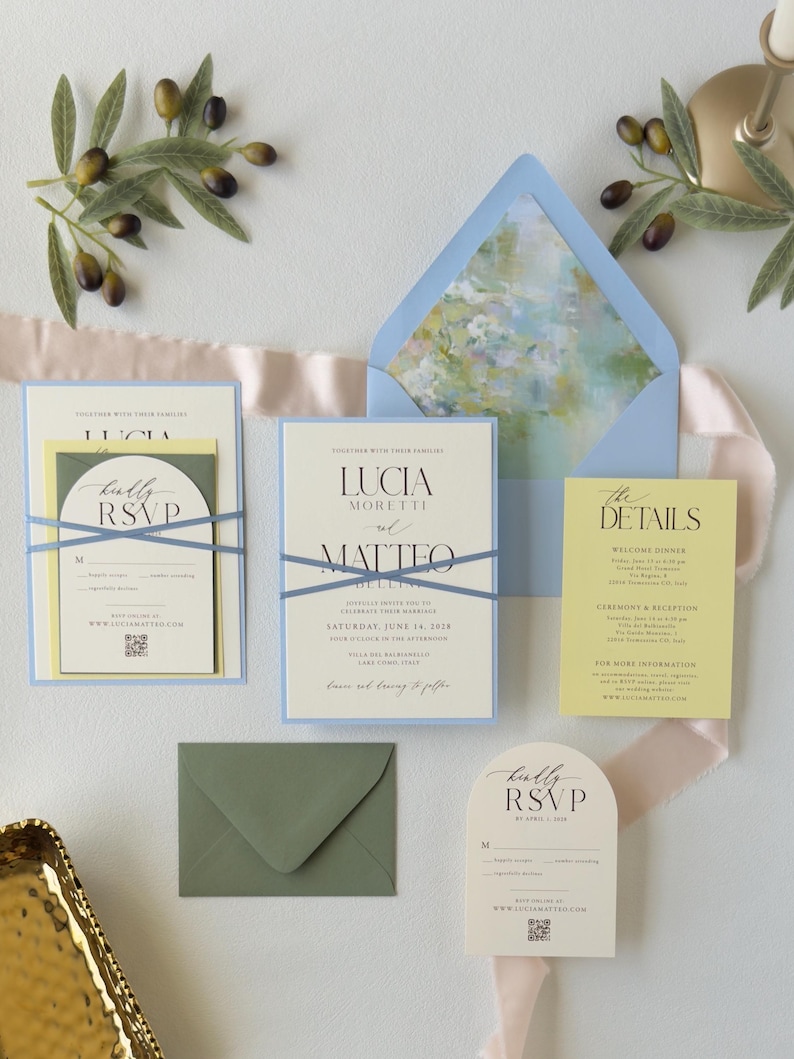 Pale blue, butter yellow and ivory Lucia wedding invitation suite featuring a layered invitation, yellow details card, ivory arch RSVP card and blue envelope with a romantic watercolor floral liner.