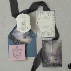 Odette storybook wedding invitation featuring delicate botanical artwork on Cloud Ivory cardstock, layered over Marina blue backing with coordinating scalloped RSVP, illustrated lake vellum jacket, and elegant dark ribbon.