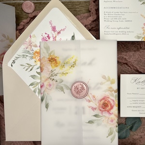 May include: A wedding invitation suite featuring a translucent vellum wrap secured with a pink wax seal, decorated with watercolor floral illustrations in shades of pink, yellow, and green, accompanied by a matching envelope and information card.