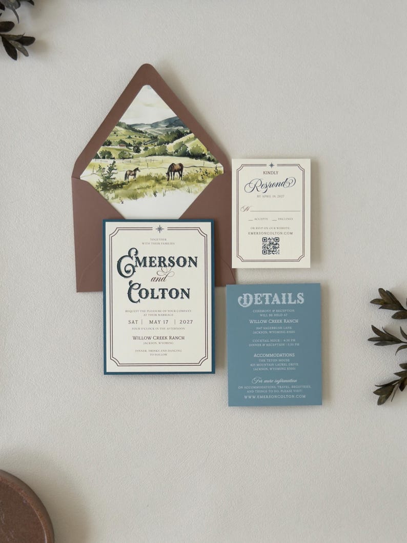 Warm brown envelope with scenic ranch landscape liner displayed with the ivory Emerson invitation, dusty blue details card and square RSVP card.