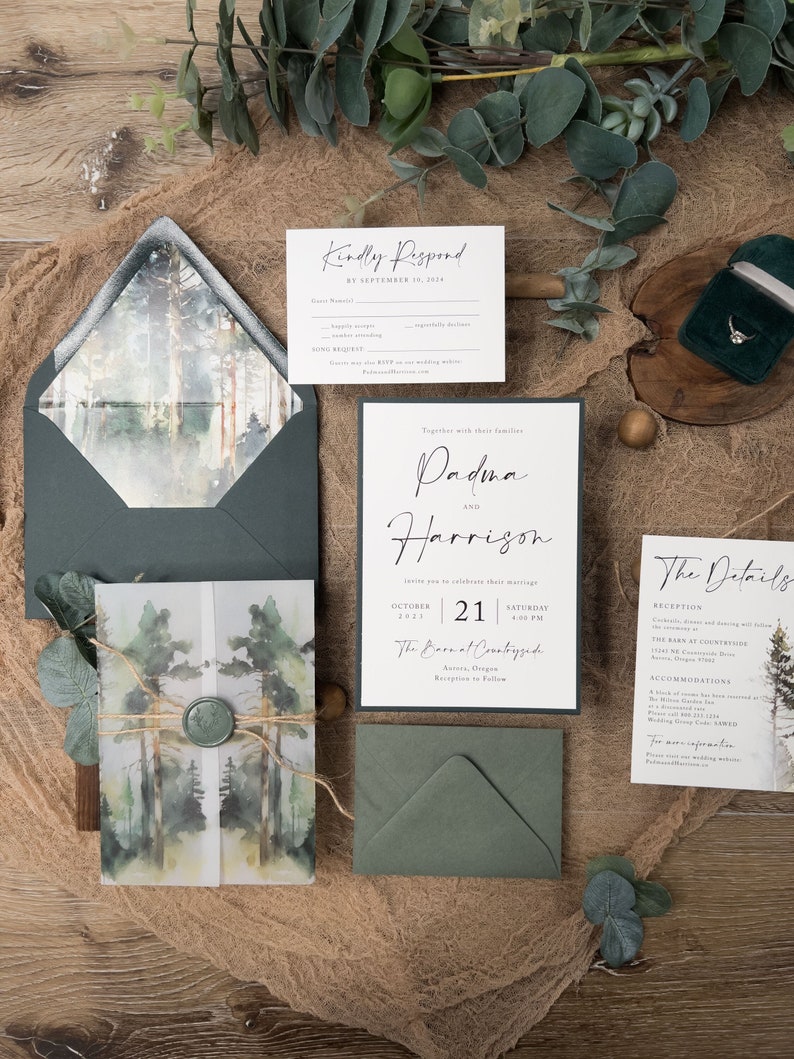 May include: A wedding invitation suite with a forest theme. The invitation features a watercolour illustration of trees and a green envelope. The RSVP card has a handwritten font and a black border. The text on the invitation reads "Together with their families, Padma and Harrison invite you to celebrate their marriage, October 21, 2023, Saturday 4:00 PM, The Barn at Countryside, Acorns, Oregon, Reception to Follow."