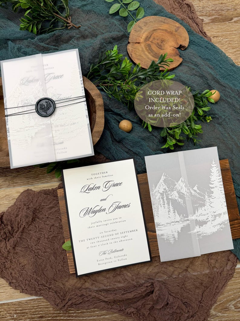 May include: Elegant wedding invitation suite featuring a main invitation with black text, a translucent overlay with a mountain scene, and a wax seal. The suite includes a cord wrap and the text "CORD WRAP INCLUDED! Order Wax Seals as an add-on!"