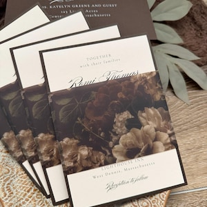 May include: A stack of cream-colored wedding invitations featuring dark brown borders and a floral belly band with dark brown and beige roses. The text reads Together with their families, Romi Thomas, Lighthouse Inn, West Dennis, Massachusetts, and Reception to follow.