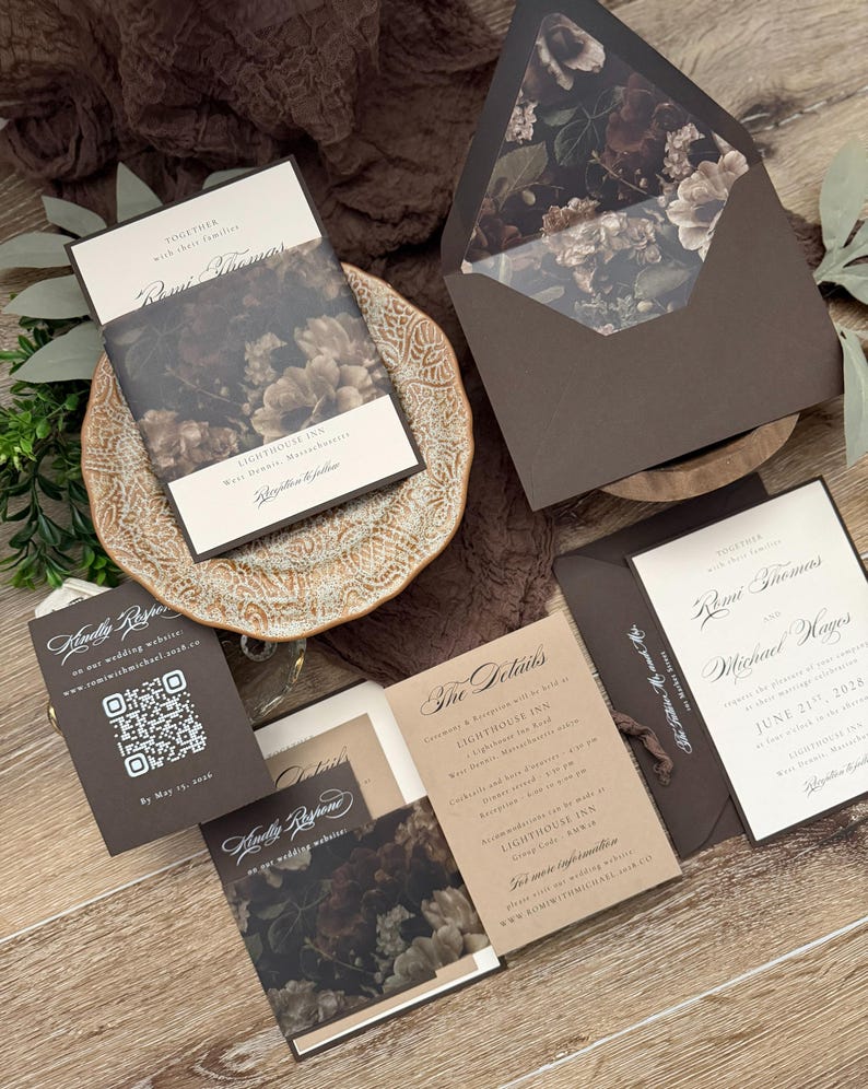 May include: A wedding invitation suite featuring dark brown envelopes with floral liners, cream-colored cards with black serif text, and a response card with a QR code. The set includes a details card and an invitation for Romi Thomas and Michael Hayes.