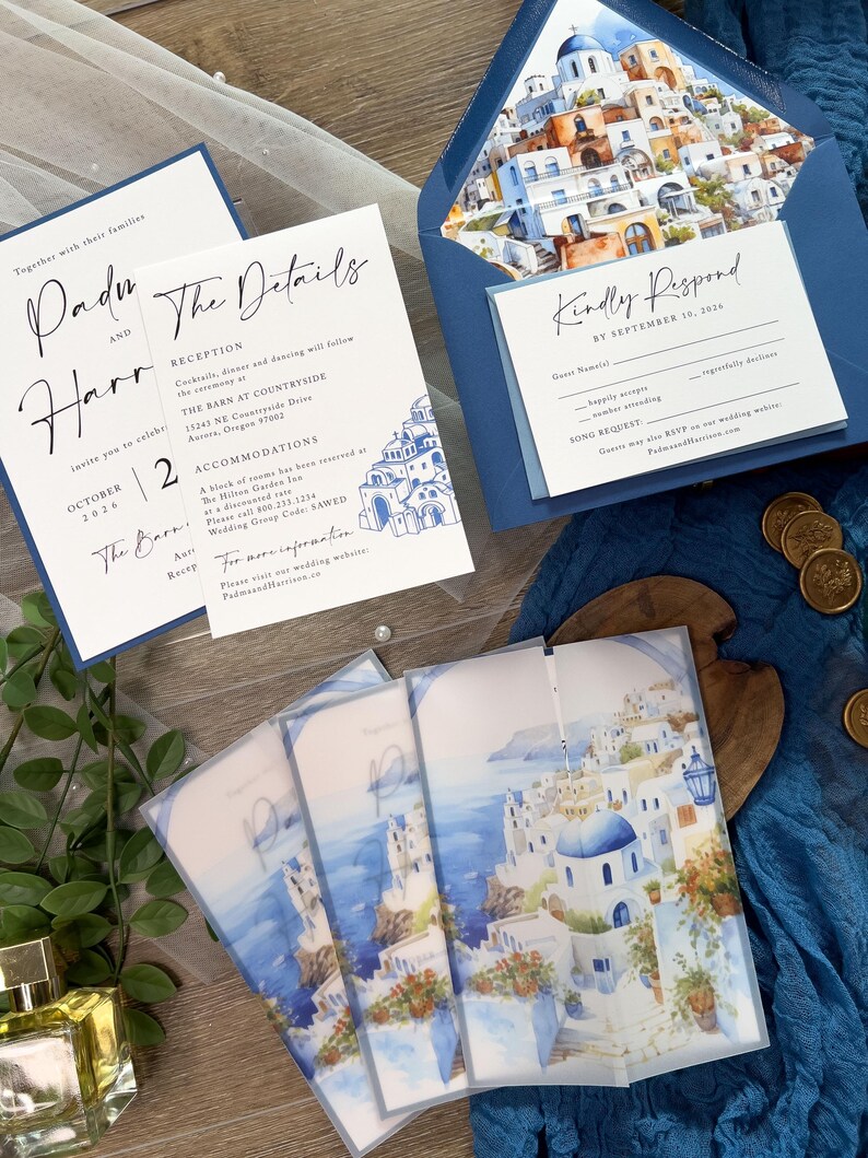 May include: Wedding invitation suite with a blue and white color scheme. The invitation features a watercolor illustration of a Greek island town. The RSVP card has a blue background with white text. The text on the invitation reads "Padi and Harr" and "The Details".