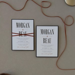 Bold Whitmore wedding invitation paired with a warm brown details card and coordinating ribbon, featuring modern editorial typography in a rich neutral wedding palette.