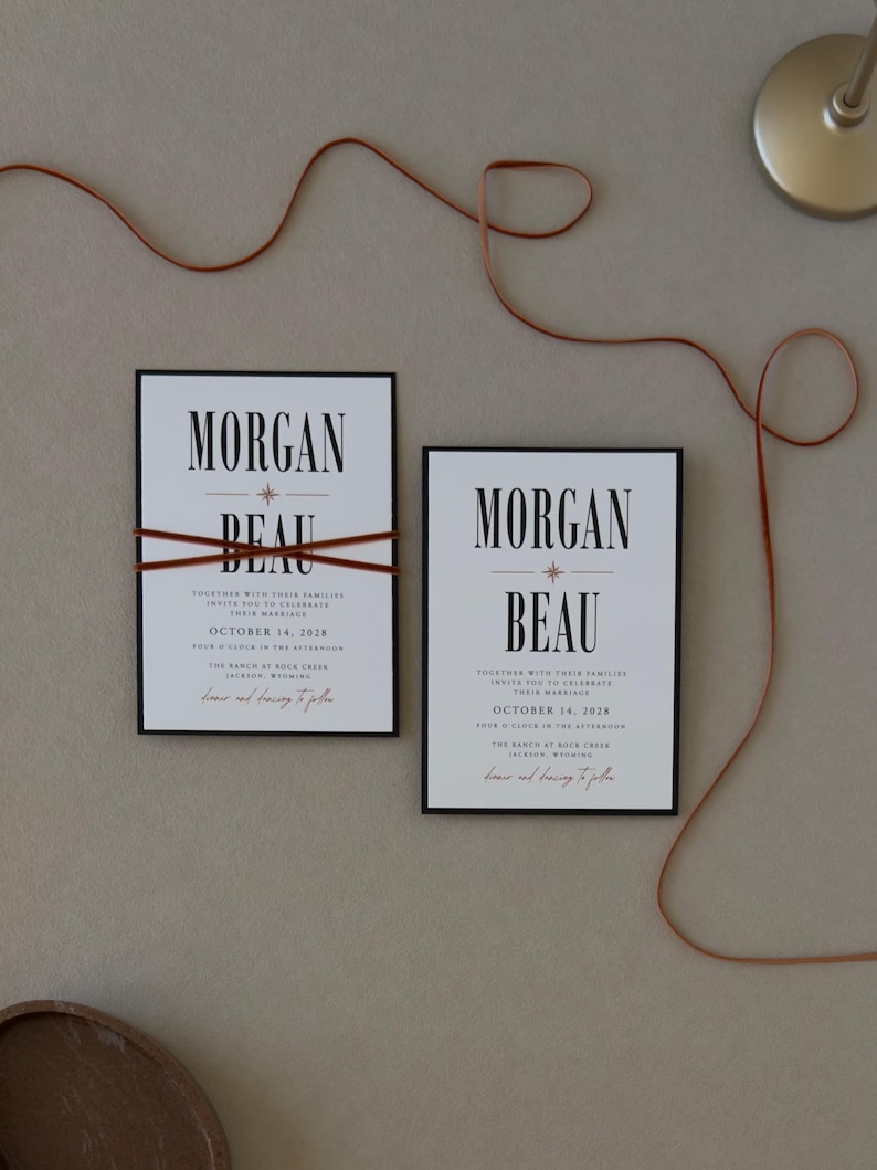 Bold Whitmore wedding invitation paired with a warm brown details card and coordinating ribbon, featuring modern editorial typography in a rich neutral wedding palette.