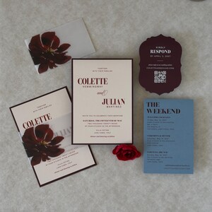 Coordinating wedding invitation cards in dusty blue, burgundy and ivory, showing the details card, scalloped RSVP and floral invitation from a romantic burgundy and blue wedding stationery suite.