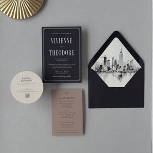Vivienne black wedding invitation suite shown in an assembly video featuring modern black stationery, taupe details card, circular RSVP card and architectural city details.