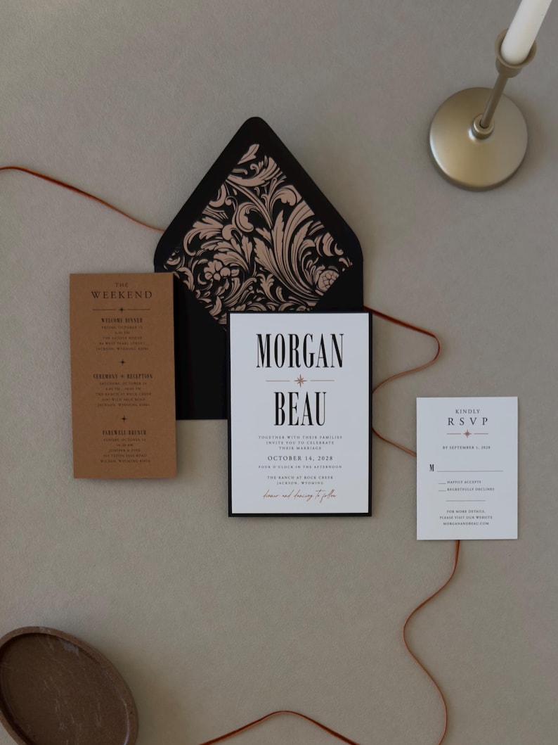 Warm brown wedding details card, white invitation and RSVP card displayed with a black envelope and dramatic botanical liner from the Whitmore wedding suite.