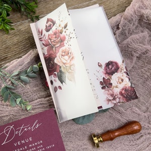 Dusty rose wedding details card with elegant typography and coordinating burgundy floral stationery.