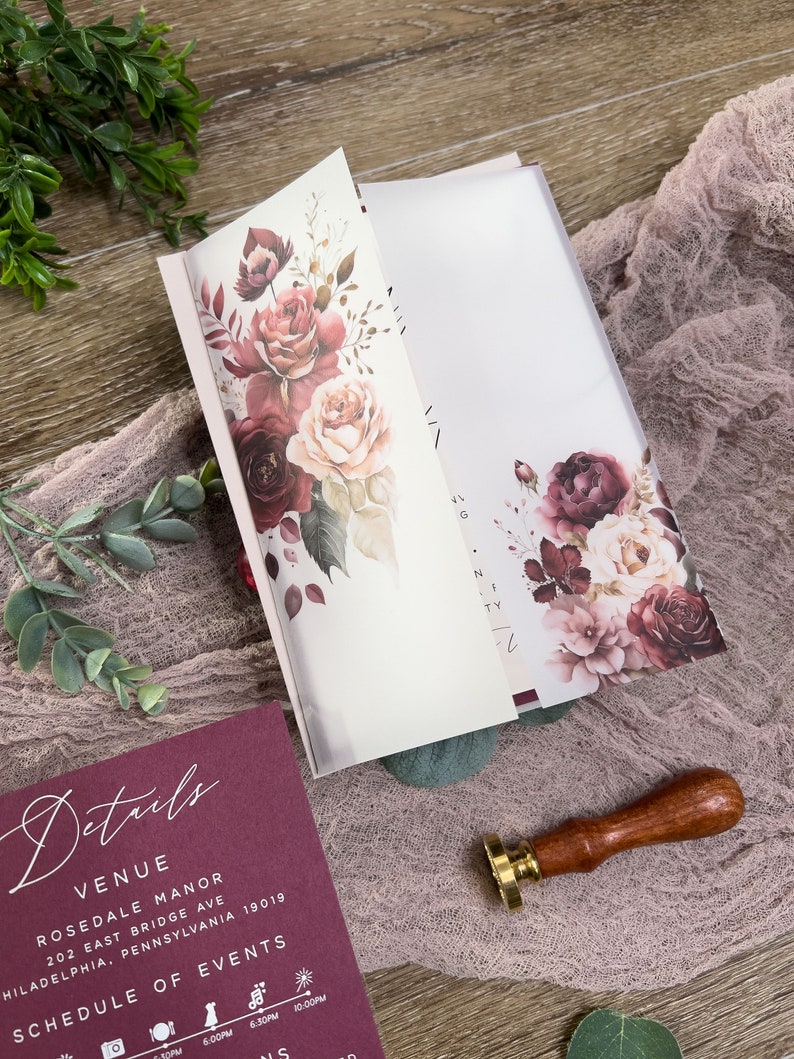Dusty rose wedding details card with elegant typography and coordinating burgundy floral stationery.