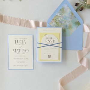 Pale blue wedding envelope opened to reveal a soft watercolor floral liner, paired with the Lucia layered invitation and ivory arched RSVP card.