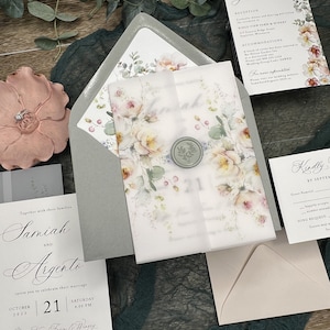 May include: A wedding invitation suite featuring a vellum wrap with a floral print and a sage green wax seal, a grey envelope, a guest details card, a response card, and a main invitation card with black text on white paper, all displaying floral motifs.