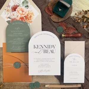 Puede incluir: Conjunto de invitaciones de boda con un esquema de color verde, blanco y naranja. La invitaci&oacute;n presenta un dise&ntilde;o floral con una paleta de colores melocot&oacute;n, naranja y rojo. El texto de la invitaci&oacute;n dice "&Uacute;nete a nosotros para la boda de Kennidy y Beau". La tarjeta RSVP es beige con un borde marr&oacute;n y dice "Por favor, responde antes del 09.25.25".