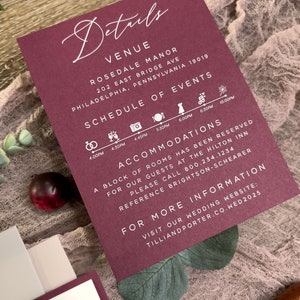 Close-up of burgundy floral wedding invitation with soft pink flowers and romantic botanical styling.