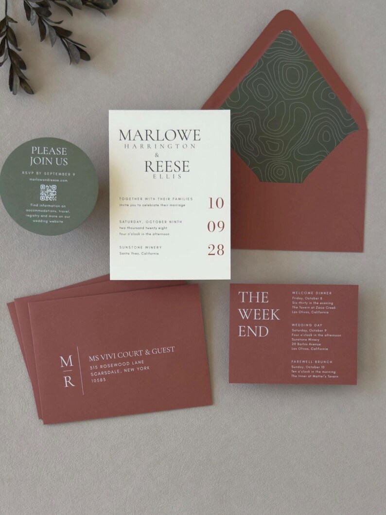 Modern terracotta and olive wedding invitation suite with ivory asymmetrical invitation, round green RSVP card, clay details cards and coordinating patterned envelope liner.