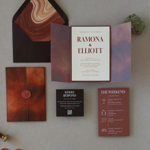 Rust, brown and ivory wedding stationery featuring a layered invitation, terracotta details card, square RSVP card and artistic abstract envelope liner.