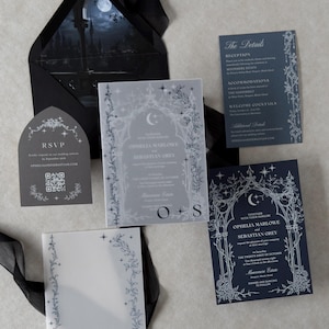 Ophelia Gothic moon wedding invitation suite featuring an Imperial Navy invitation with intricate white ink celestial and floral artwork, Marina details card, Dark Grey tombstone-shaped RSVP card, Ebony A7 envelope with moonlit castle liner, and printed vellum jacket.
