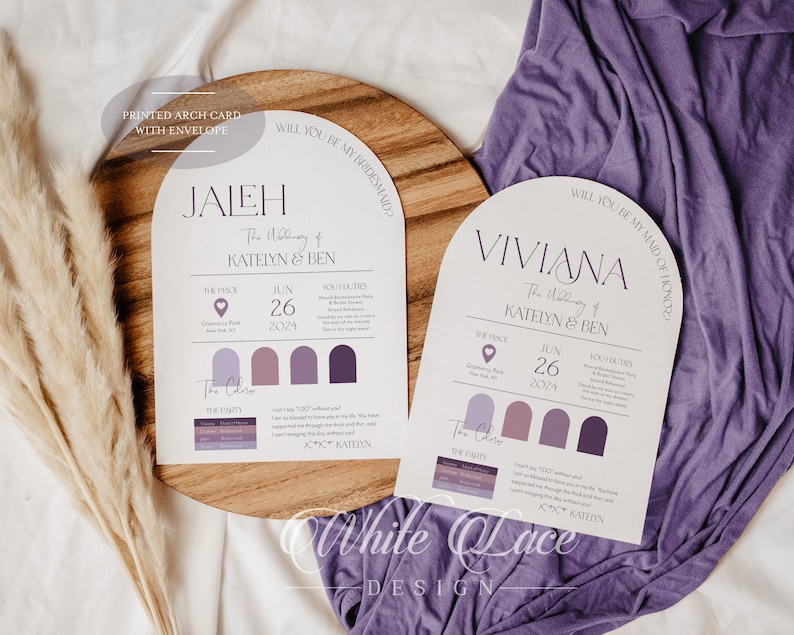 May include: Two white arch-shaped cards with purple text and accents. The text on the cards reads "Will you be my bridesmaid?" and "Will you be my maid of honor?" The cards are on a wooden surface with a purple fabric in the background.